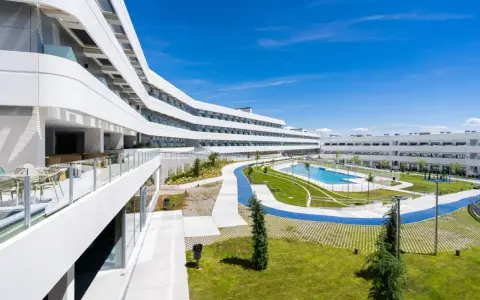 Modern residence in Madrid with curved white buildings, a pool, and green spaces.