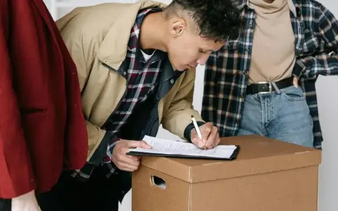 Jóvenes firmando un contrato de mudanza, quizás relacionado con la ley de arrendamientos urbanos.