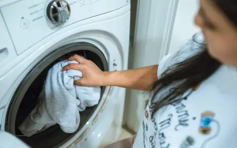 Mano saca ropa de lavadora. Espera que la lavadora haga mucho ruido al centrifugar.