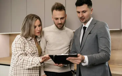Pareja revisa documentos con un agente inmobiliario, discutiendo los términos de un subarriendo de vivienda.