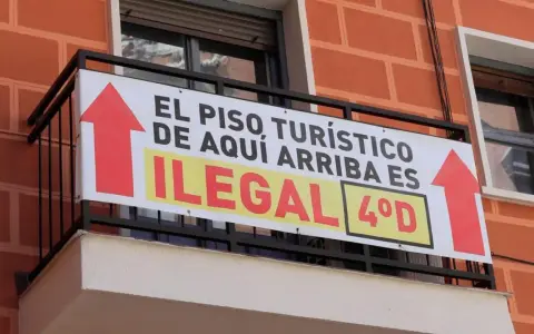 Cartel en balcón: "El piso turístico de aquí arriba es ilegal". Prohibición pisos turísticos.