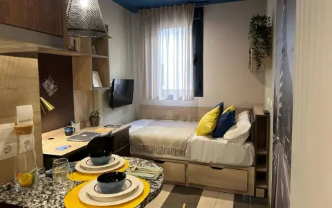 Estudio moderno en Livensa Living Madrid Aravaca con cama, escritorio, TV y mesa.