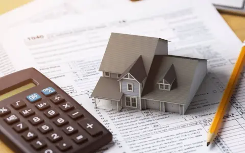Casa modelo sobre formulario 1040, calculadora y lápiz. El arte 3 lau se relaciona con la planificación fiscal.