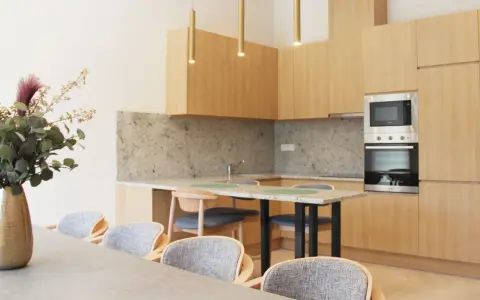 Estudio moderno en Livensa Living Studios Málaga Feria, con cocina equipada, encimera de granito y comedor con sillas cómodas.