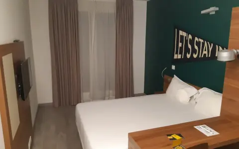 Habitación moderna en The Student Hotel Paris. Cama blanca, escritorio de madera y decoración "Let's Stay In".