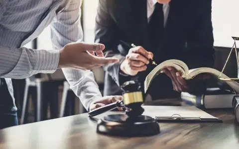 Abogados discuten un caso de demanda, ejecución, desahucio y lanzamiento. Martillo de juez y balanza de la justicia en primer plano.
