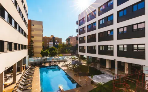 La residencia de estudiantes Livensa Living Sevilla luce su piscina y zonas comunes bajo el sol.