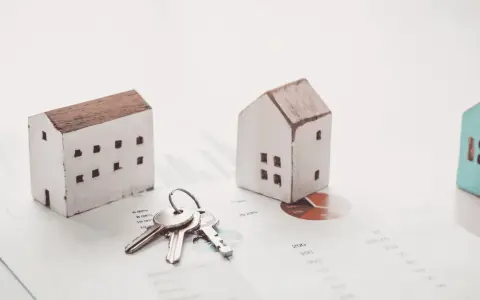 Maquetas de casas y llaves sobre gráficos financieros. El arte 17 lau sugiere una inversión inmobiliaria.