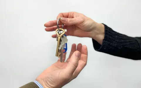 Manos intercambian llaves, simbolizando un nuevo hogar o un contrato de subarrendamiento.