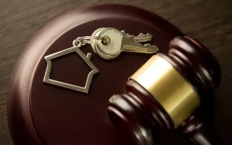 Martillo de juez y llaves con llavero de casa, simbolizando el lanzamiento de desahucio a terceros ocupantes.