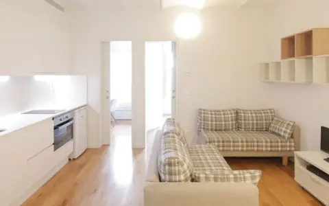 Cocina y salón modernos en la residencia Unihabit Sant Cugat. Sofás a cuadros y estanterías flotantes.
