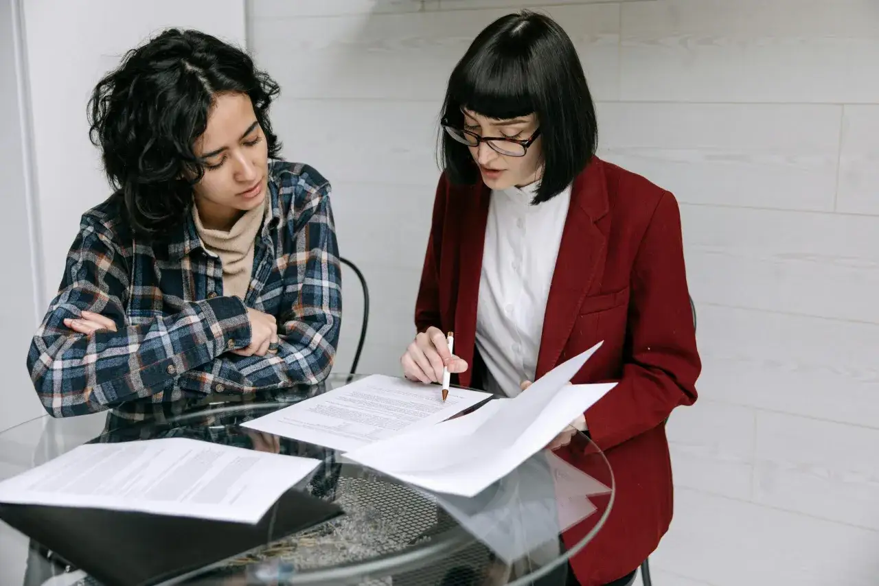 Dos personas analizan un contrato, discutiendo la diferencia entre alquiler de temporada y vivienda habitual.