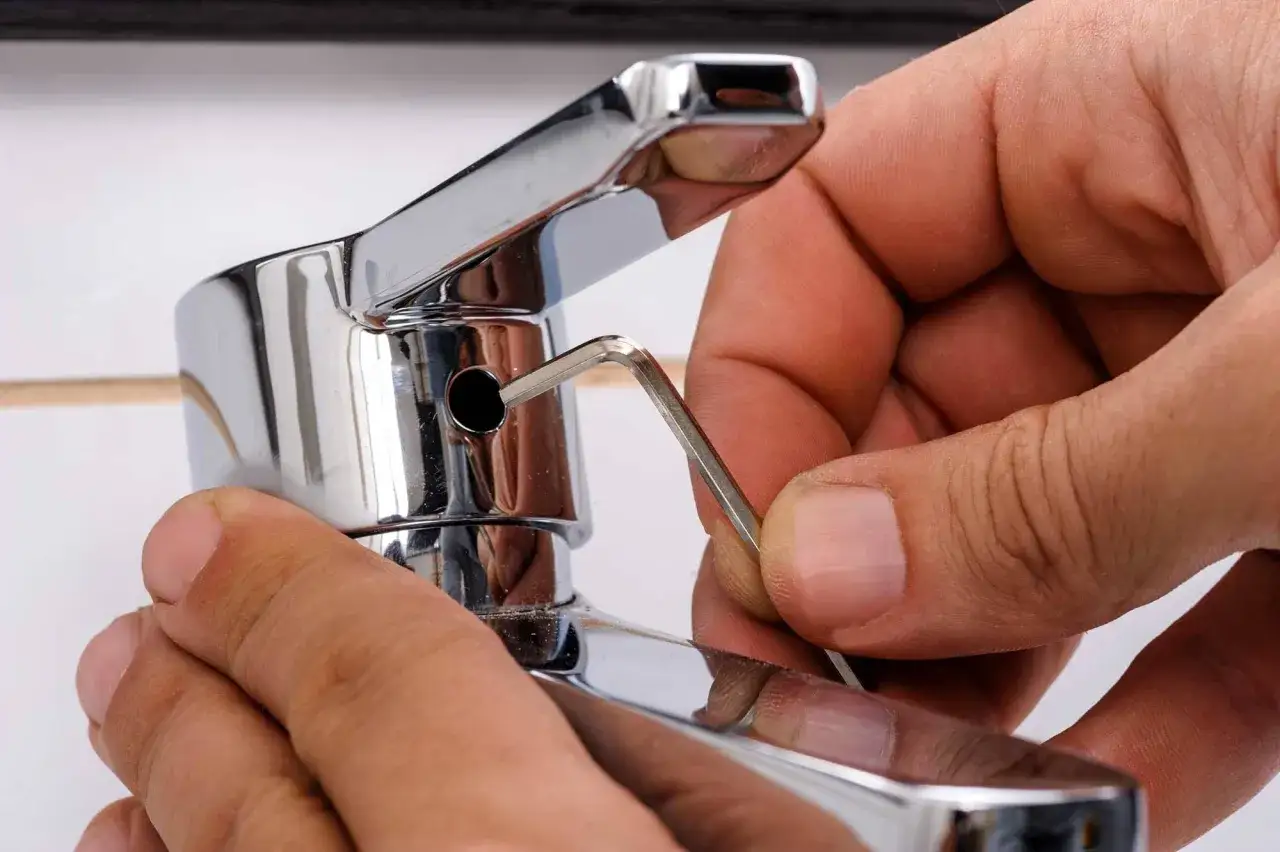 Mano ajustando un grifo que gotea con una llave Allen.