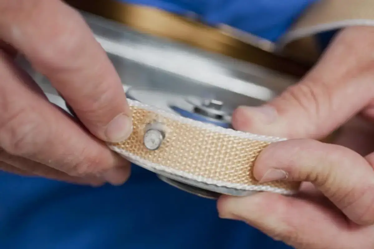 Manos ajustando la cuerda de una persiana, mostrando cómo arreglar la cuerda de una persiana con un remache.