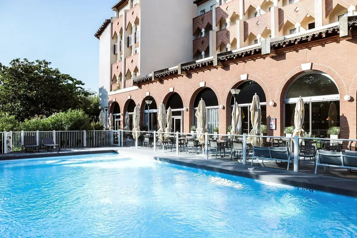Piscina y terraza con mesas y sombrillas en el exterior del student hotel Toulouse.