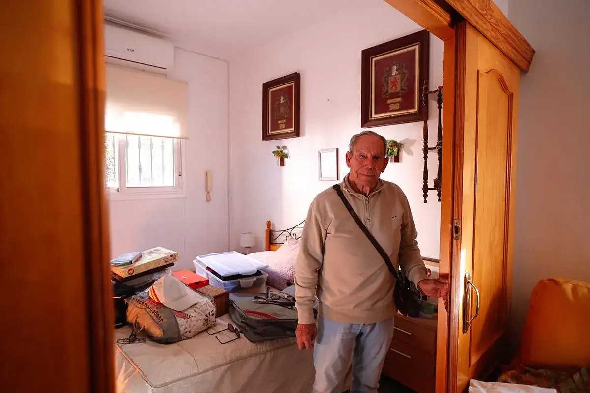 Un hombre mayor, con cara de preocupación, está en una habitación desordenada. Parece que me quieren echar de la habitación.