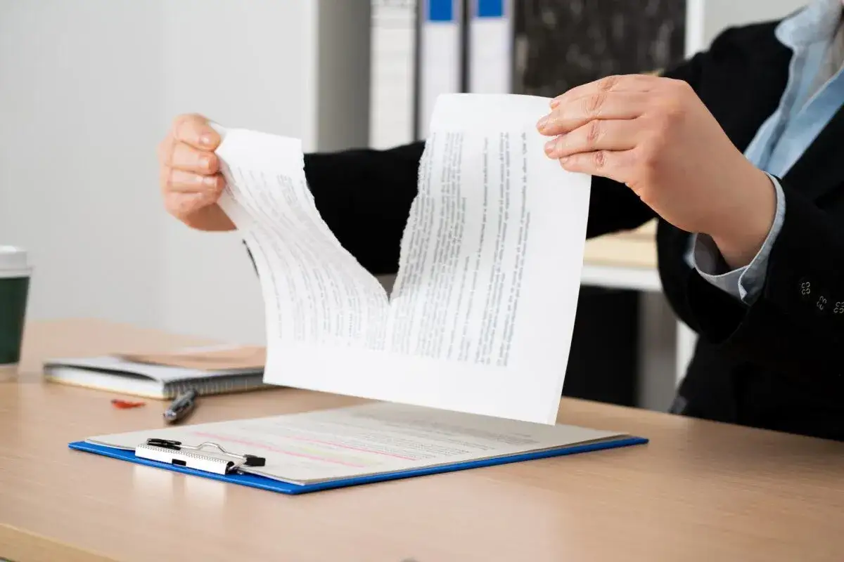 Manos rasgando un documento, simbolizando el desistimiento de contrato de alquiler.
