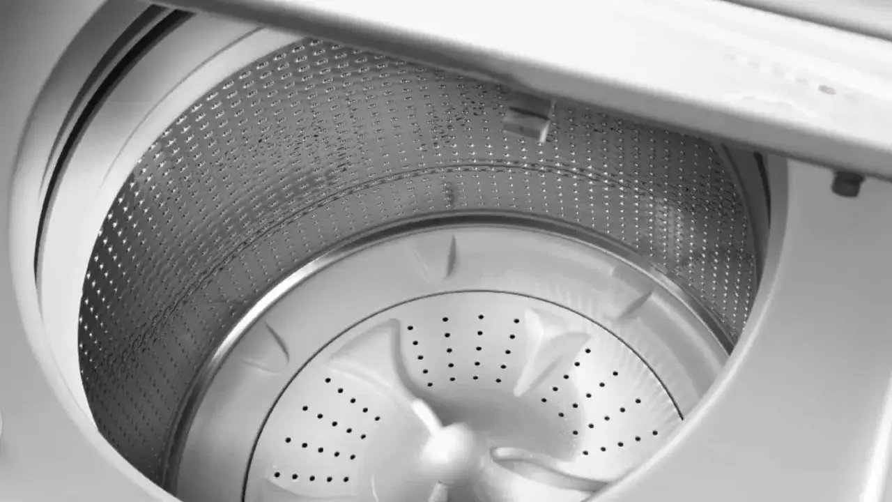 Interior de una lavadora de carga superior, con el tambor metálico perforado y el agitador central. ¿Por qué mi lavadora no centrifuga?