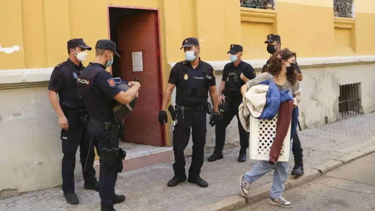 Policías observan a una mujer con ropa y una cesta, mientras se pregunta si me pueden desalojar si tengo niños.