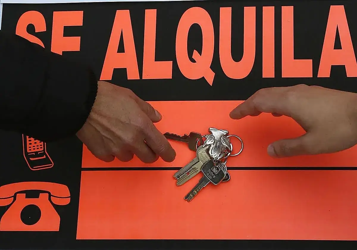 Manos intercambiando llaves frente a un cartel
