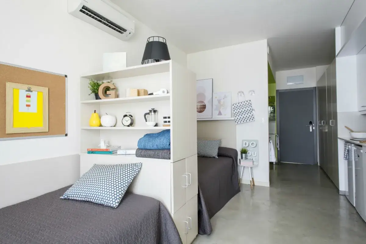 Habitación en residencia la salle con dos camas, estanterías y un pequeño rincón de cocina.