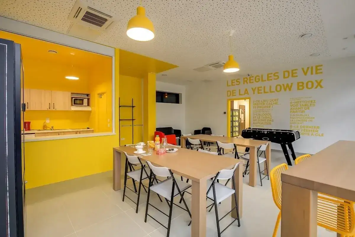 Sala común de ecla villejuif con cocina abierta, mesas, futbolín y reglas de convivencia escritas en la pared.