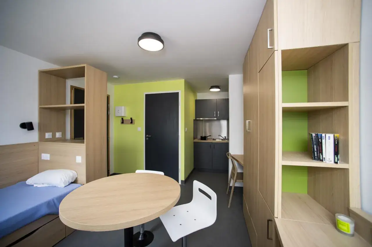 Habitación de crous con cama, mesa, cocina y armarios.
