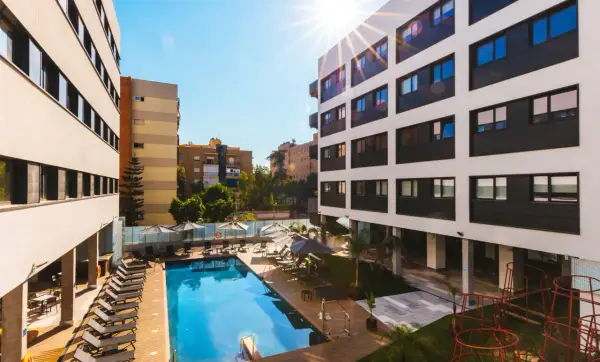 La residencia de estudiantes Livensa Living Sevilla luce su piscina y zonas comunes bajo el sol.