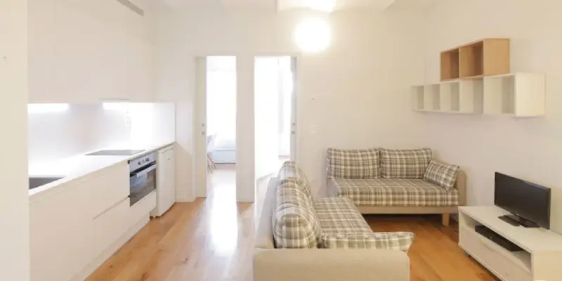 Cocina y salón modernos en la residencia Unihabit Sant Cugat. Sofás a cuadros y estanterías flotantes.